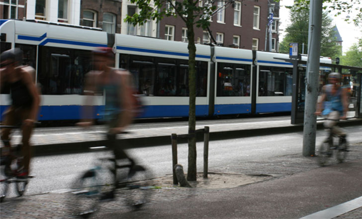 Ciclistas por un carril bici junto a un tranvía en una ciudad