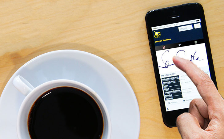 Un usuario practica su firma electrónica en un dispositivo móvil situado junto a una taza de café