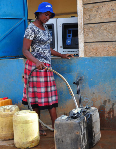 Una mujer se abastece de agua obtenida de uno de los cajeros automáticos que dispensan agua potable y cuyo pago se hace mediante teléfono móvil