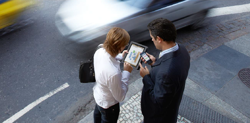 Dos personas con dispositivos móviles que intercambian información.