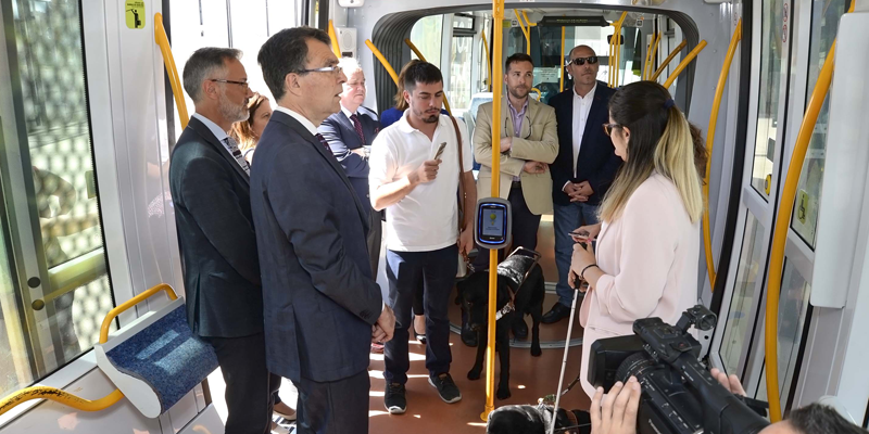 Interior del tranvía de Murcia en la presentación del sistema de visión artificial que prueba una mujer invidente, junto a las autoridades presentes.