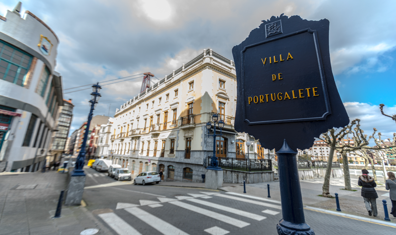 Calle de la ciudad con un cartel que pone Villa de Portugalete en primer plano