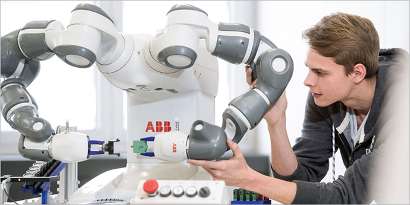 Un chico joven maneja un robot industrial