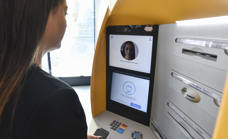 Una clienta de CaixaBank prueba uno de los cajeros automáticos en los que está disponible la tecnología de reconocimiento facial para identificarse a la hora de sacar dinero. 