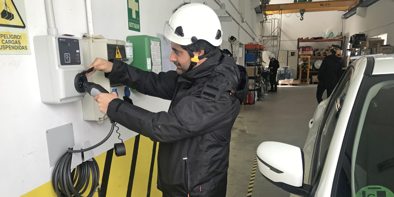 Un operario instala uno de los puntos de recarga eléctrica en una nave o garaje de un parque eólico.