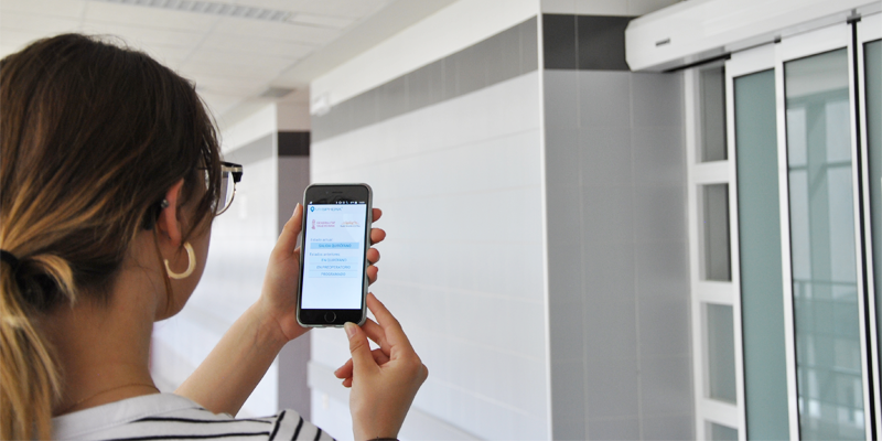 Una mujer mira la aplicación en su móvil delante de la zona de quirófanos de un hospital.