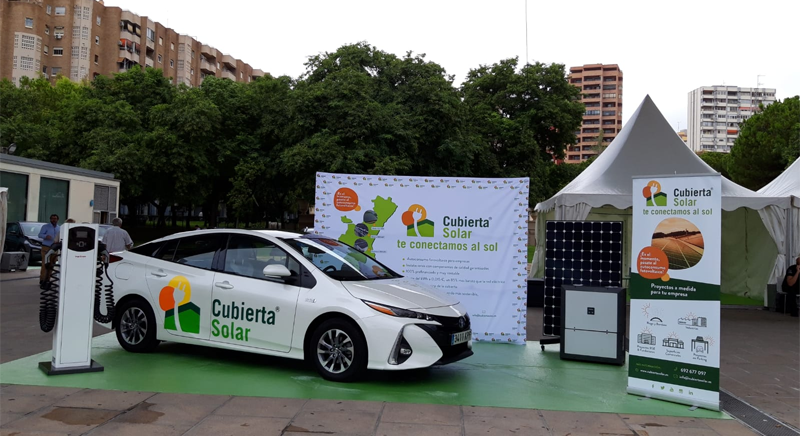 coche fotovoltaico y punto de recarga eléctrica en un stand al aire libre.