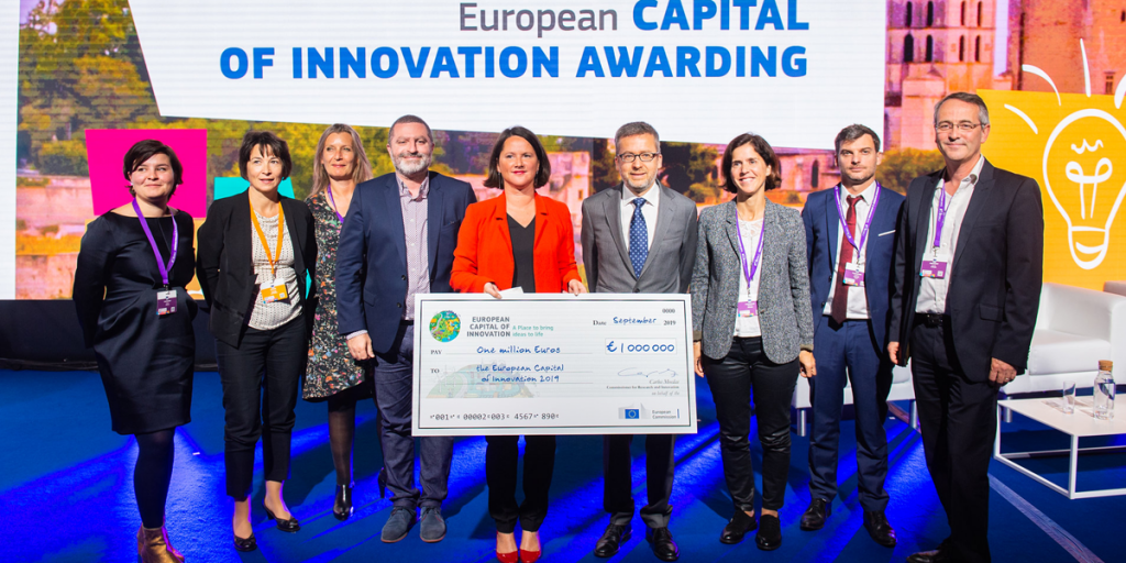 La alcaldesa de Nantes, junto a otras personas, posa con el cheque simbólico de un millón de euros, premio que recibe como Capital Europea de la Innovación 2019.