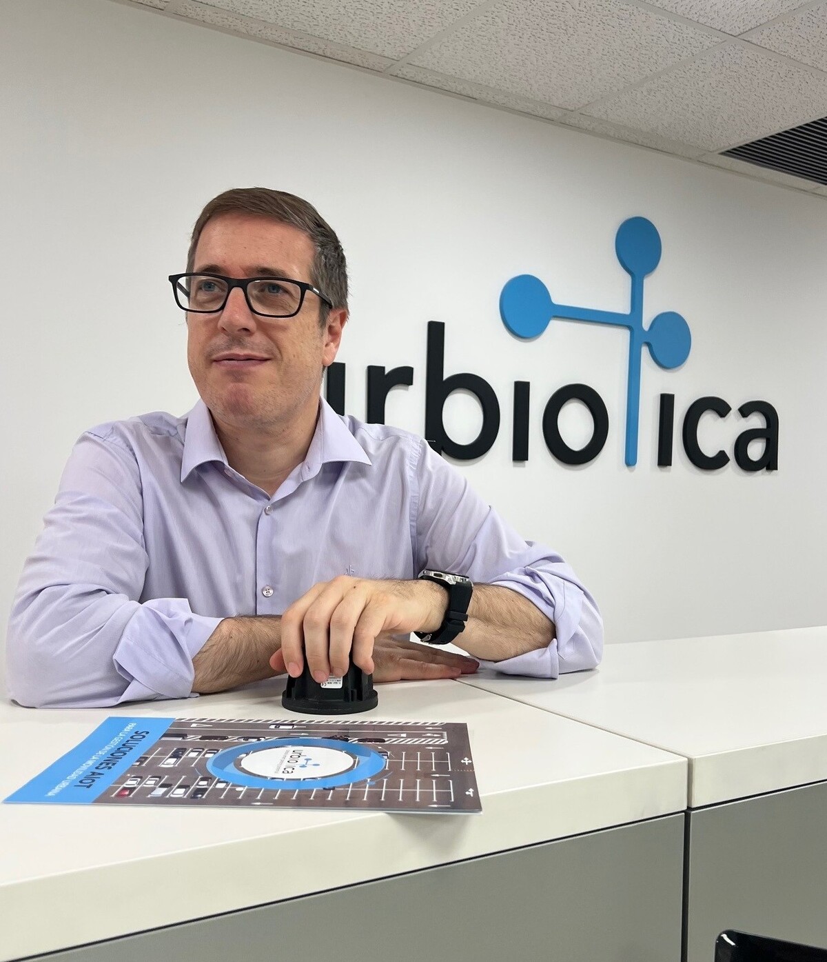 Marc Boher, Chief Operating Officer de Urbiotica, sentado ante una mesa con el logotipo de la empresa al fondo.